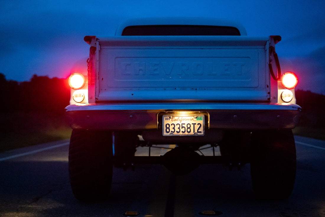 A white truck driving down a road at night