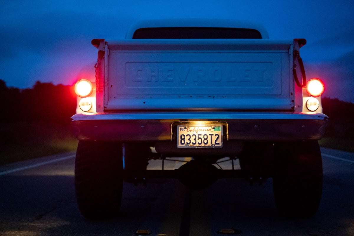 A white truck driving down a road at night