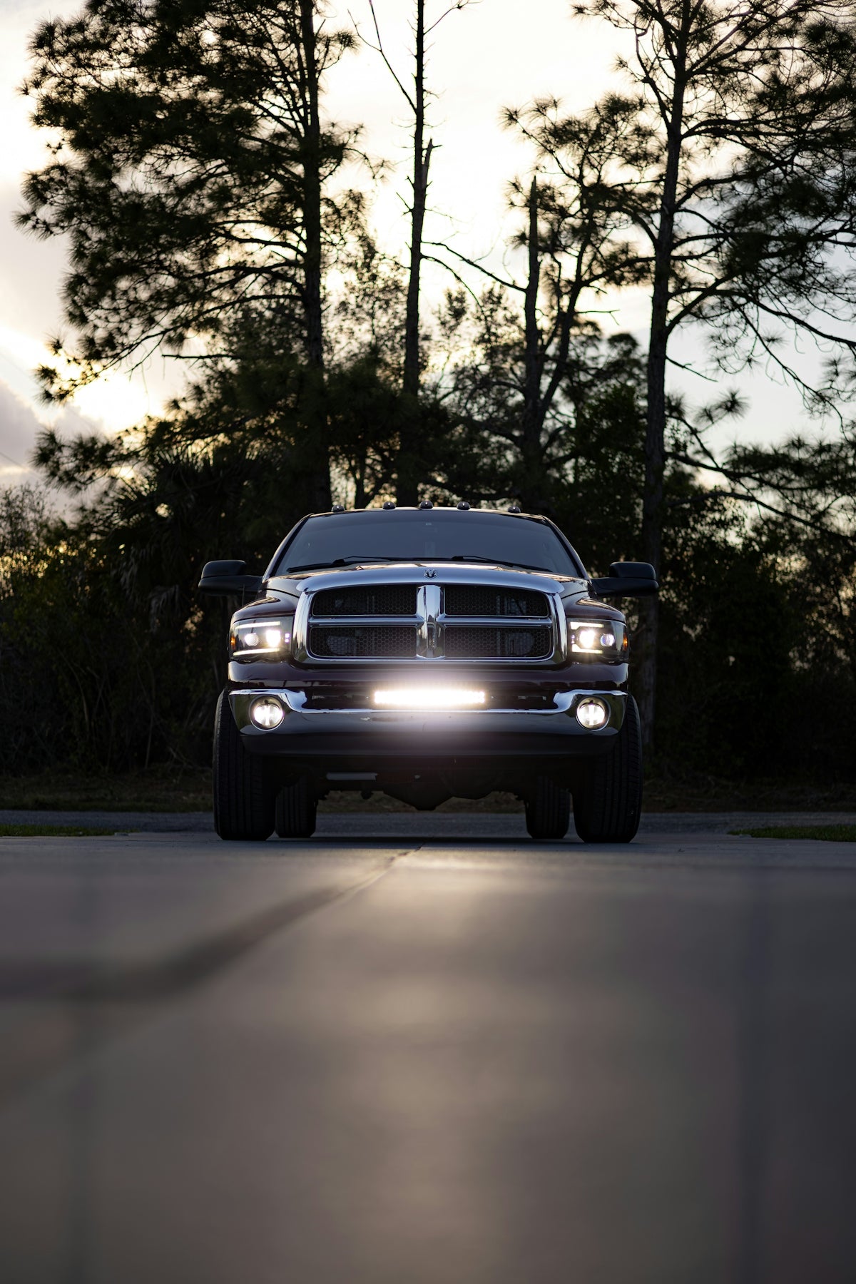 A dark pickup truck with its headlights on