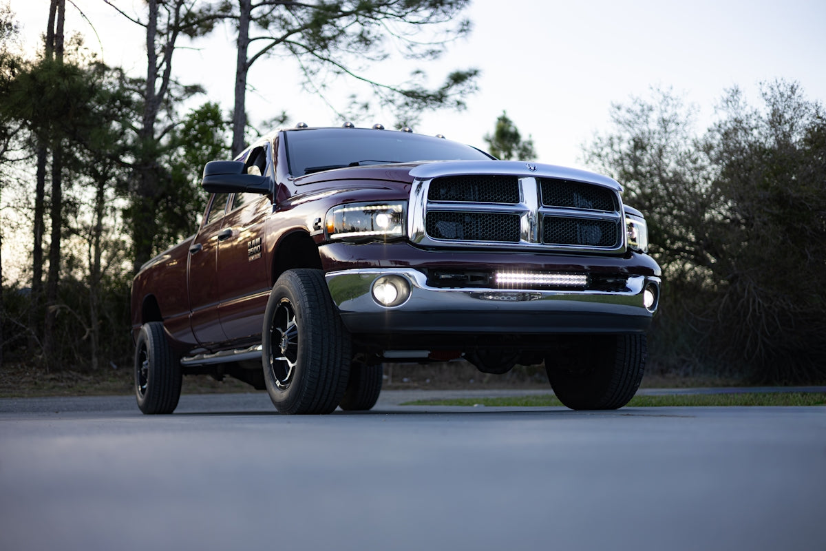 Maroon pickup truck parked outdoors with trees in background
