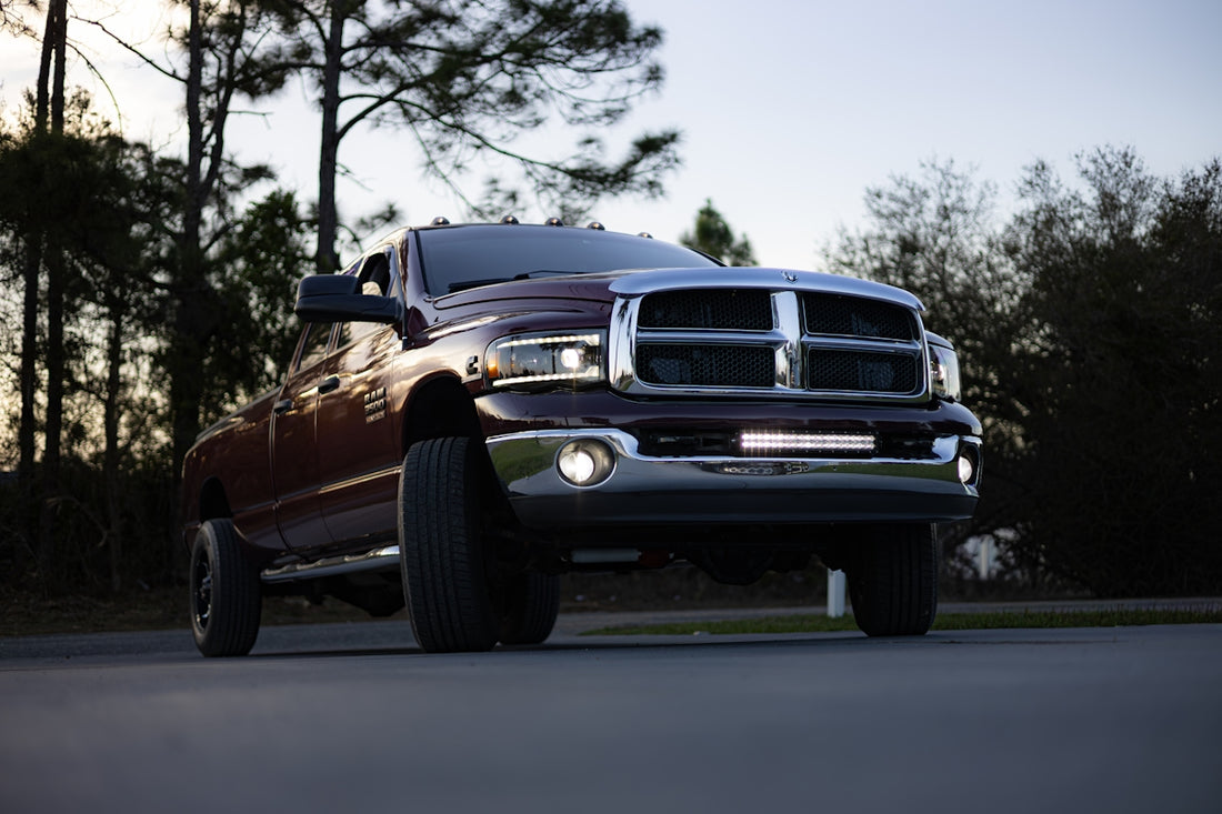A maroon pickup truck driving on a road.